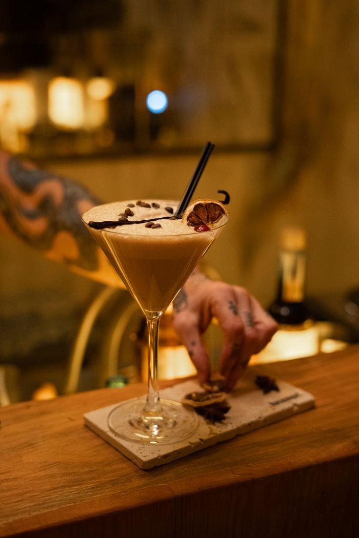 Artisan cocktail with elegant presentation at a stylish bar, captured with a tattooed bartender.